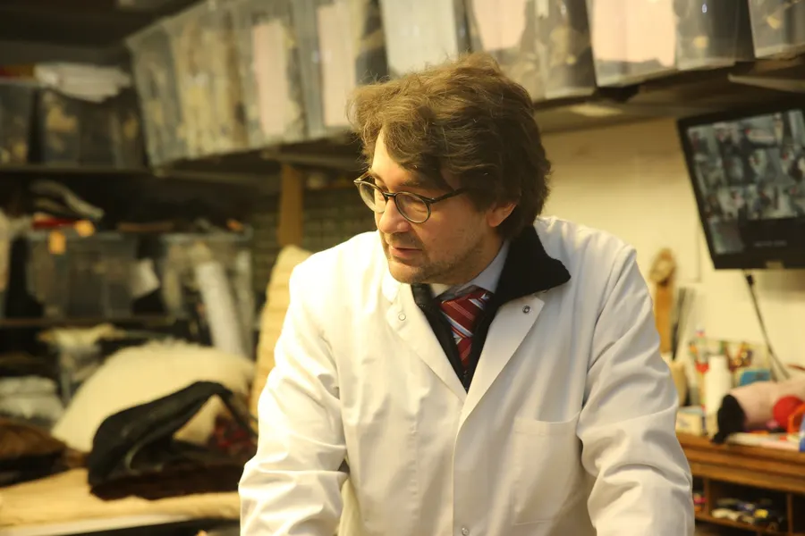 Lionel Fuchs à l'établi de l'atelier New Embert, devant les rayonnages de fourrures