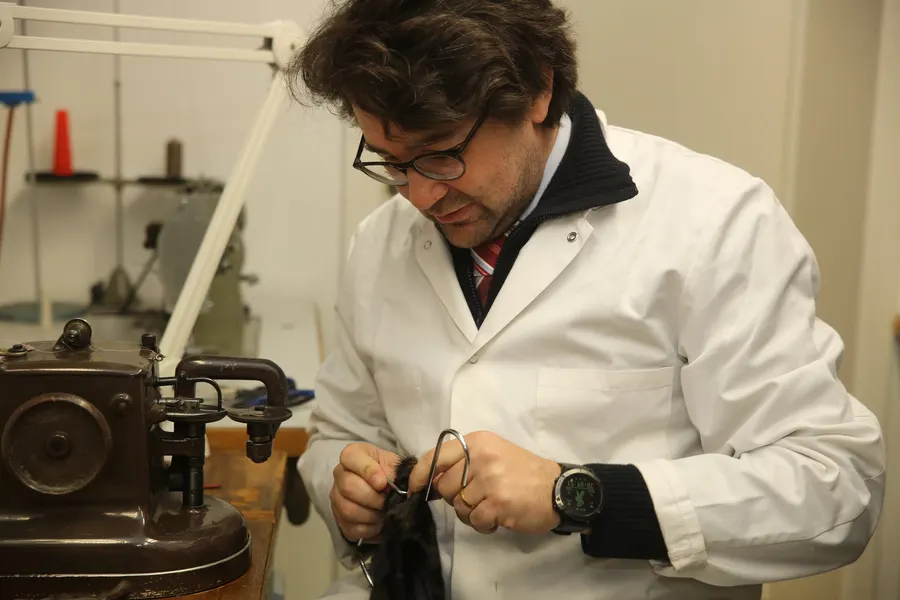 Lionel Fuchs working on a piece of black fur beside a furrier's sewing machine in the New Embert atelier