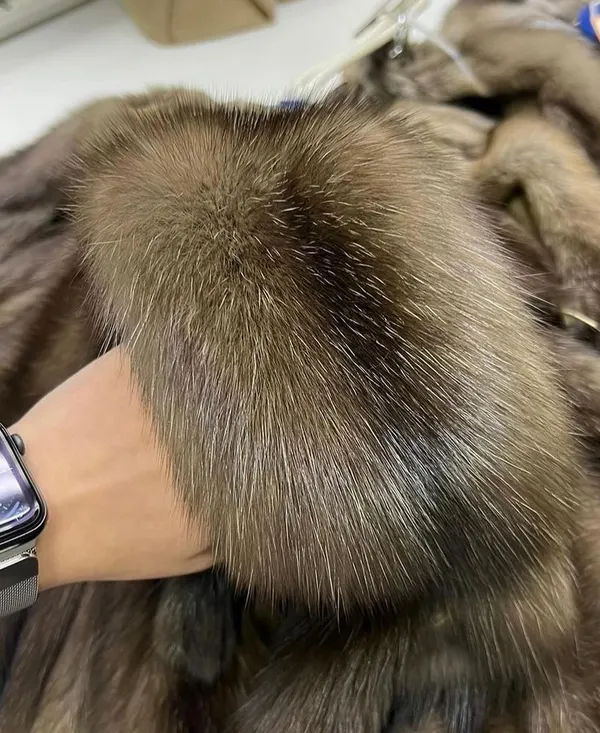 Une main passe dans le poil d'un manteau de fourrure pour en juger la densité